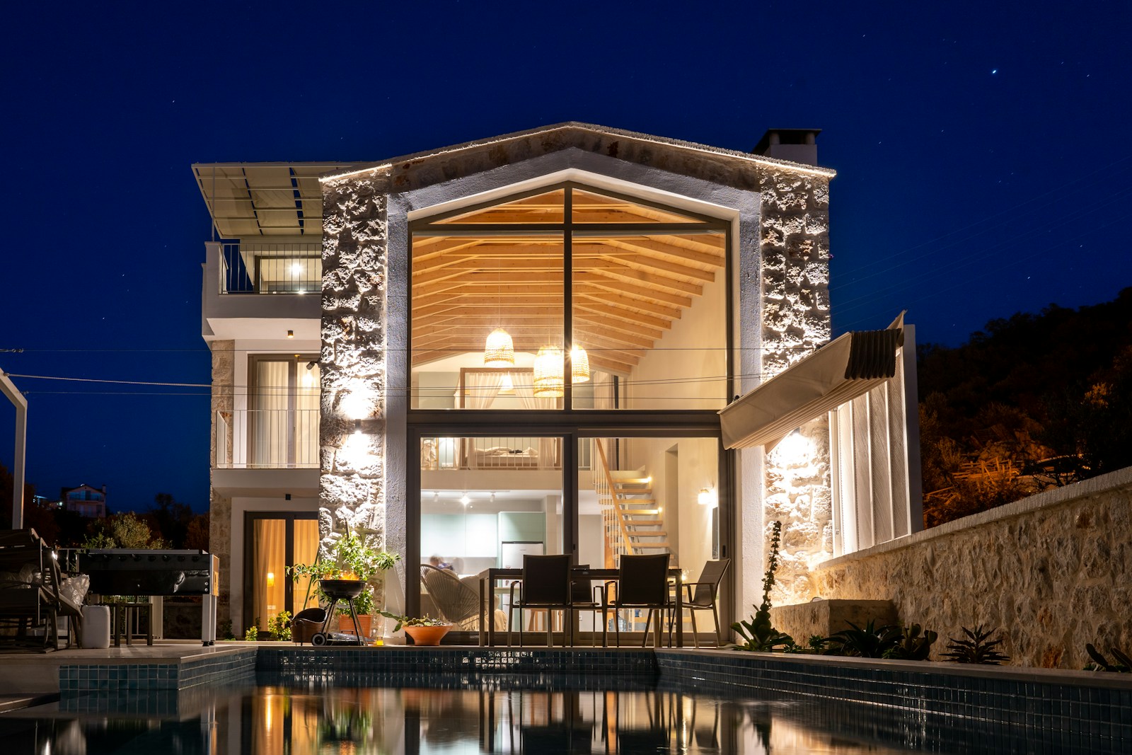 Stone villa lit at night beside its pool